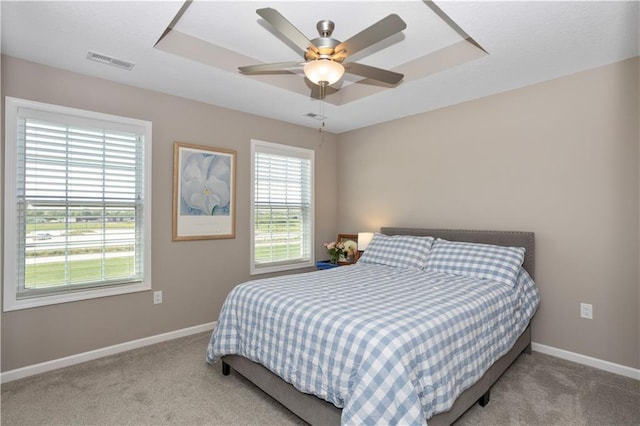 carpeted bedroom with a tray ceiling and ceiling fan