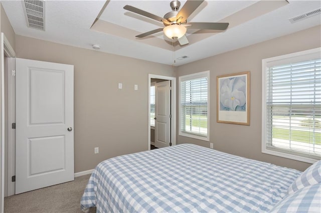 bedroom featuring a raised ceiling, ceiling fan, and light carpet