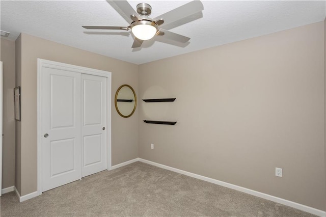 unfurnished bedroom featuring ceiling fan, light colored carpet, and a closet