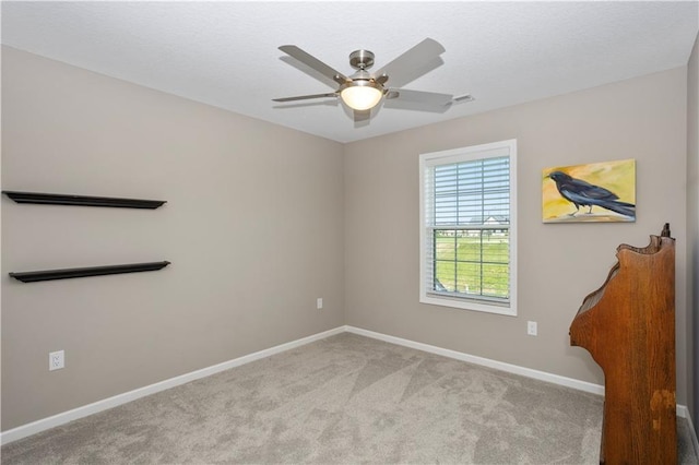 carpeted spare room with ceiling fan