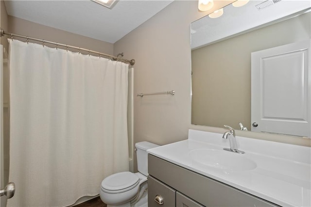 bathroom with curtained shower, vanity, and toilet