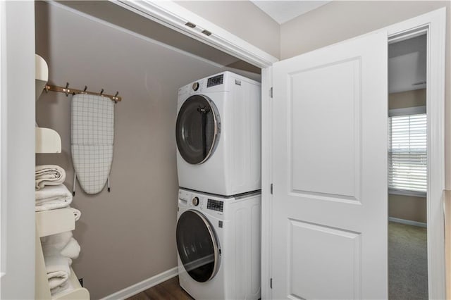 clothes washing area with stacked washing maching and dryer