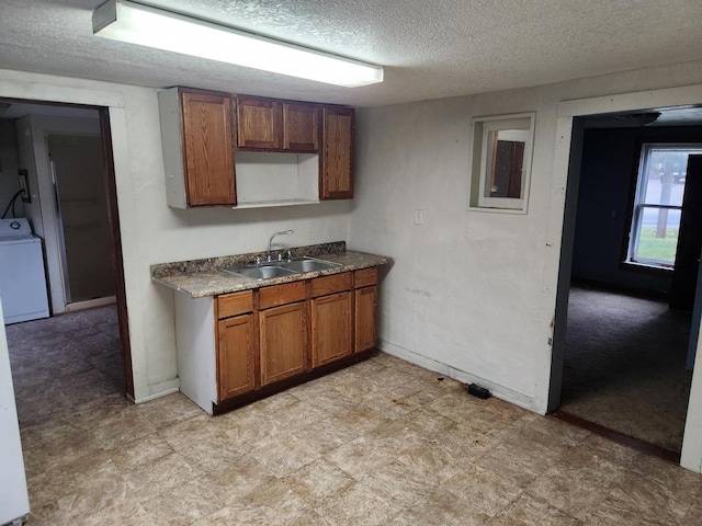 kitchen with sink, a textured ceiling, and washer / dryer