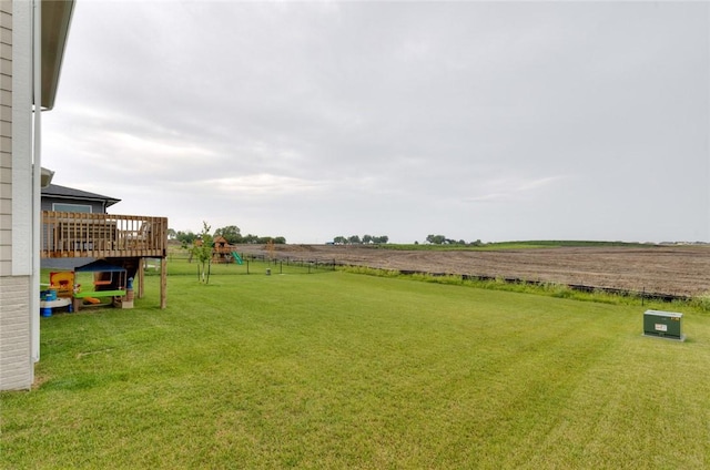 view of yard with a playground, a wooden deck, and a rural view