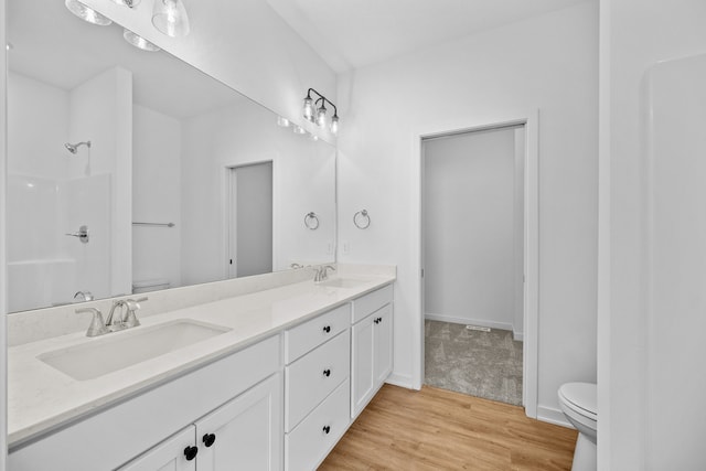 bathroom with hardwood / wood-style flooring, vanity, toilet, and a shower