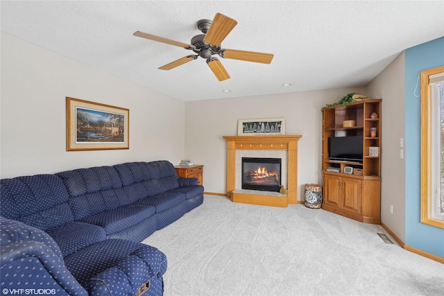 living room with a fireplace, light carpet, a textured ceiling, and ceiling fan