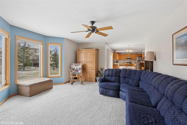 living room with a textured ceiling, ceiling fan with notable chandelier, and light carpet