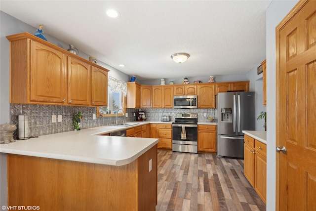 kitchen featuring kitchen peninsula, backsplash, stainless steel appliances, sink, and light hardwood / wood-style floors