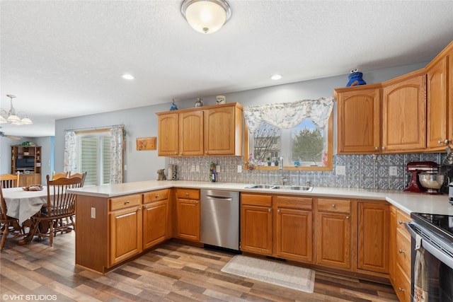 kitchen featuring pendant lighting, sink, light hardwood / wood-style flooring, kitchen peninsula, and stainless steel appliances