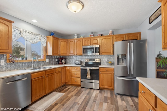 kitchen with backsplash, sink, wood-type flooring, and stainless steel appliances