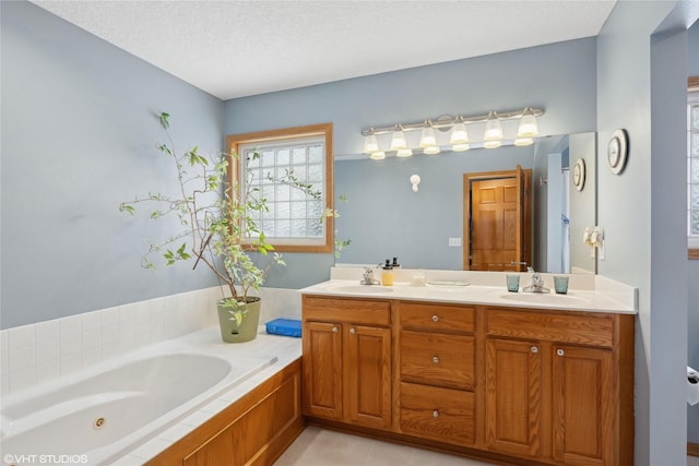 bathroom with tile patterned floors, vanity, a tub to relax in, and a textured ceiling