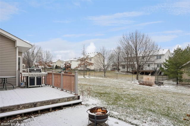 yard layered in snow with a playground, a deck, and a fire pit