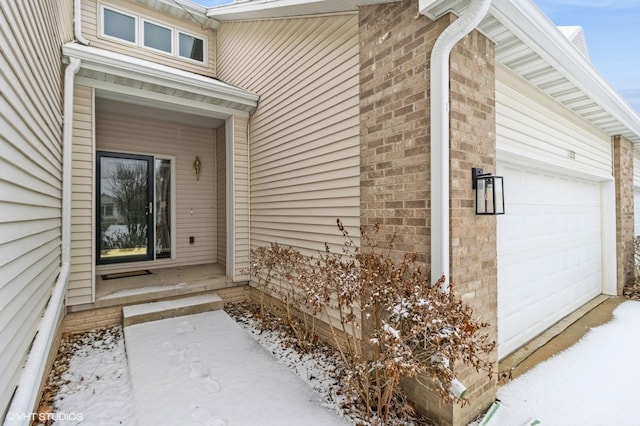 snow covered property entrance featuring a garage