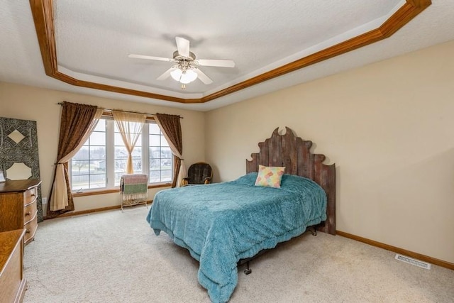 carpeted bedroom with a raised ceiling, ceiling fan, and crown molding