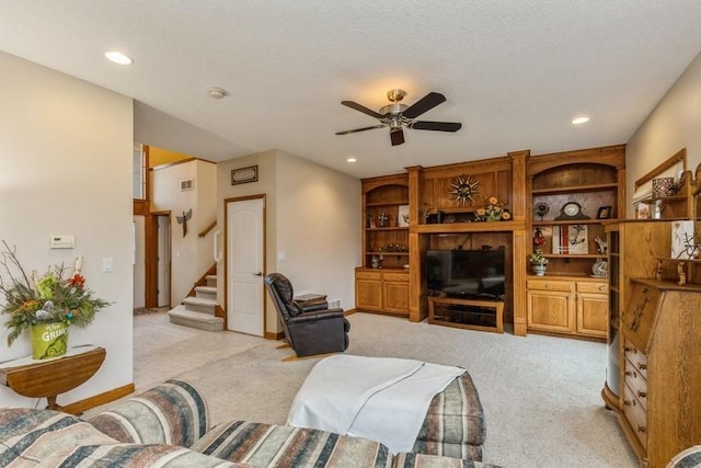 living room featuring built in shelves, a textured ceiling, light colored carpet, and ceiling fan