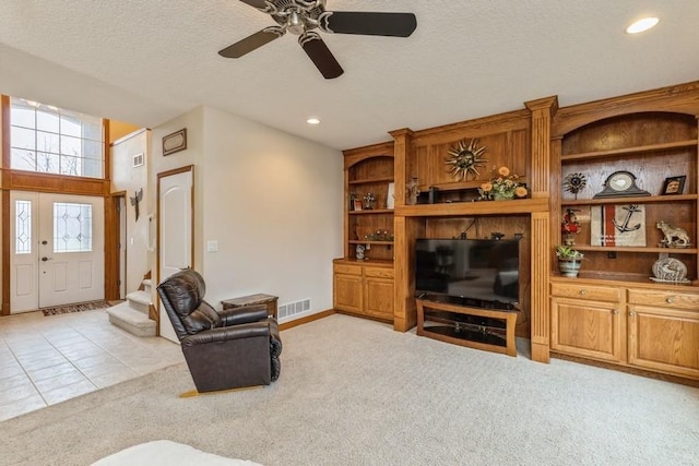 living room with ceiling fan, light colored carpet, and a textured ceiling