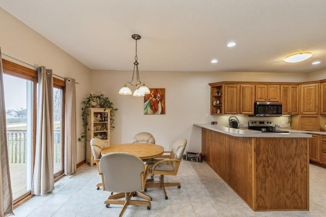 kitchen with kitchen peninsula, stainless steel appliances, sink, a notable chandelier, and hanging light fixtures