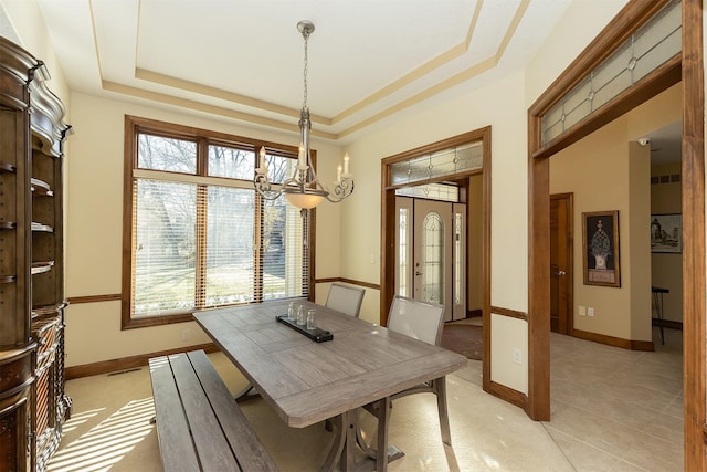 tiled dining area featuring a tray ceiling and a notable chandelier