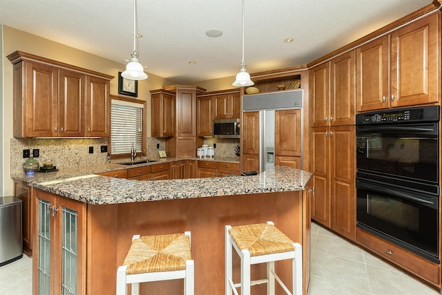 kitchen featuring a breakfast bar, black double oven, sink, paneled built in refrigerator, and hanging light fixtures