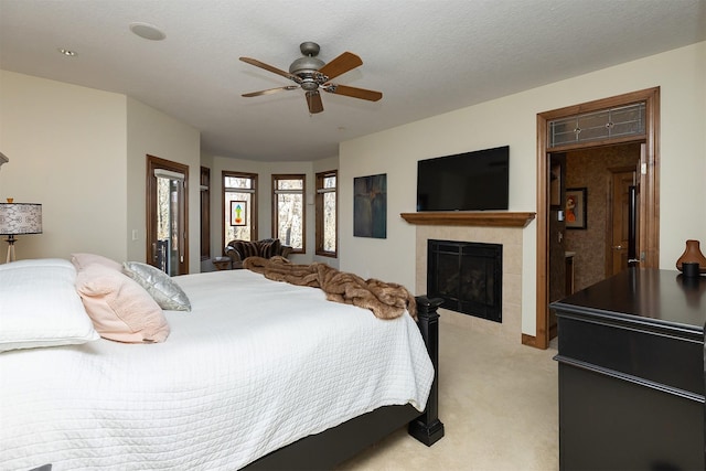 bedroom with light carpet, a textured ceiling, ceiling fan, and a fireplace