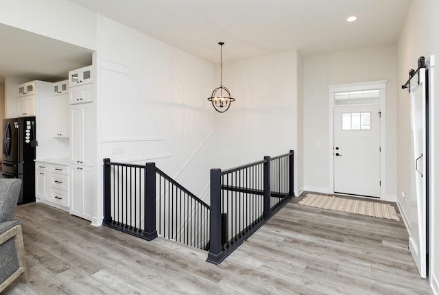 entrance foyer featuring a barn door, a chandelier, and light hardwood / wood-style floors