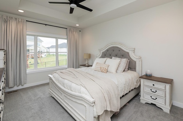 carpeted bedroom featuring a raised ceiling and ceiling fan