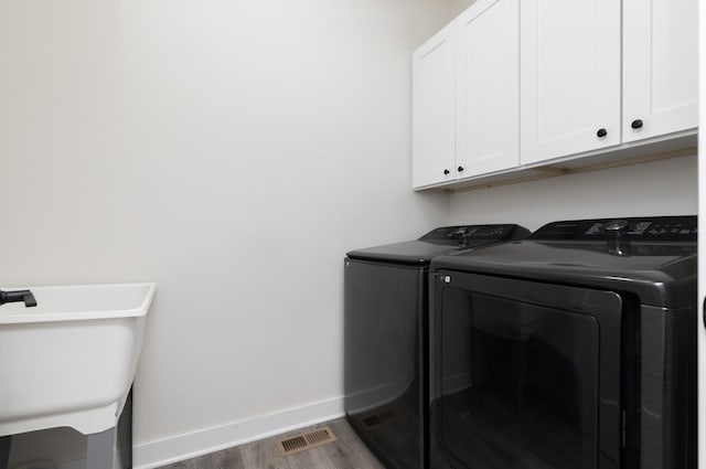 washroom featuring washing machine and dryer, sink, cabinets, and dark hardwood / wood-style floors