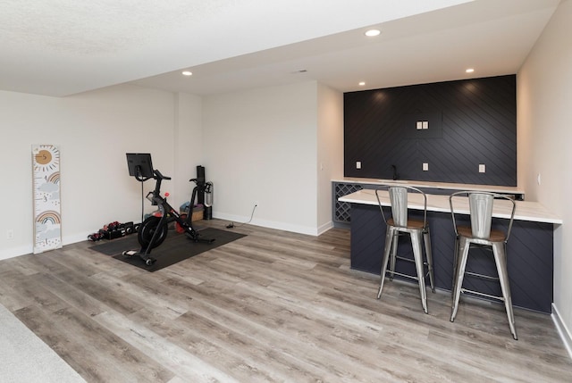 workout room featuring light wood-type flooring and indoor bar