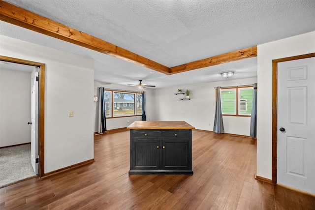 kitchen featuring wood-type flooring, a kitchen island, a textured ceiling, and ceiling fan