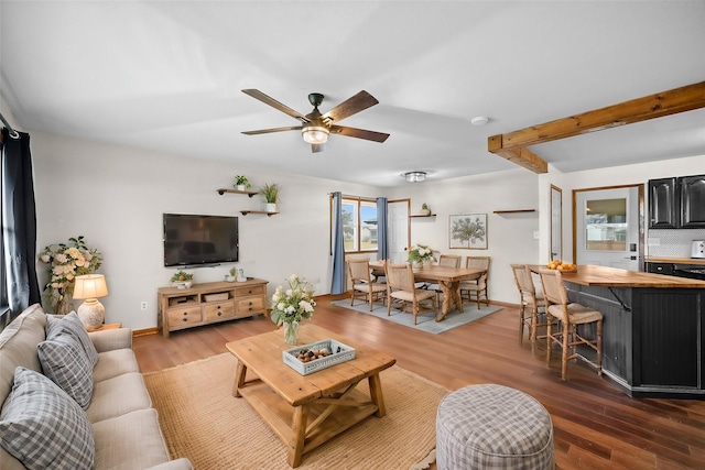 living room featuring hardwood / wood-style floors, ceiling fan, and beamed ceiling