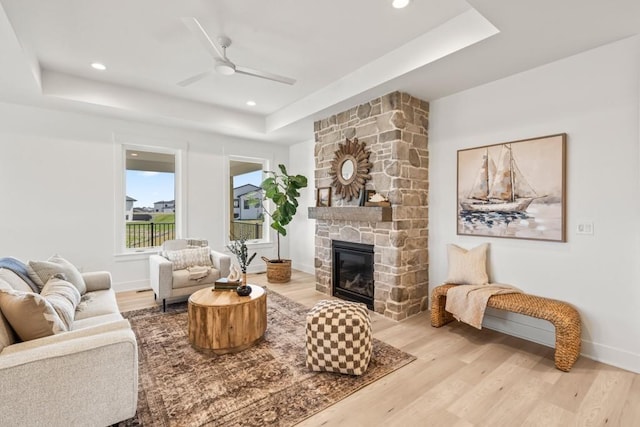 living room featuring a raised ceiling, a fireplace, and light hardwood / wood-style flooring