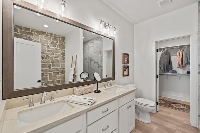 bathroom featuring wood-type flooring, vanity, toilet, and walk in shower