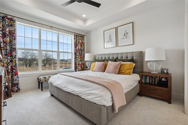 bedroom with ceiling fan, a raised ceiling, and light carpet