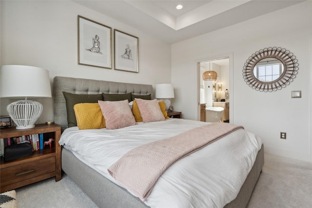 carpeted bedroom with ensuite bathroom and a raised ceiling