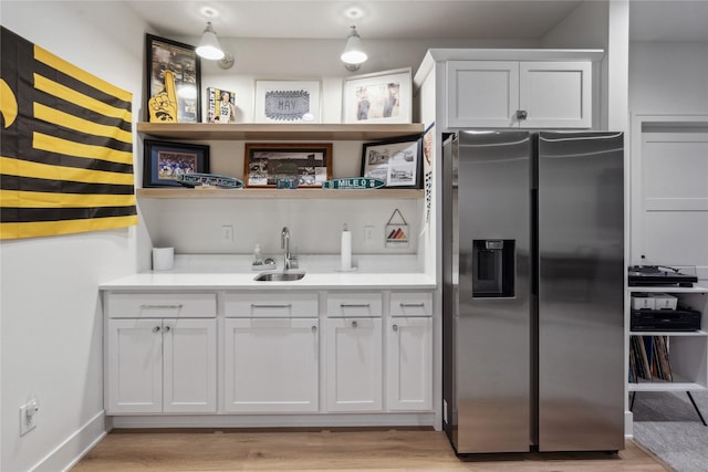 kitchen with white cabinetry, light wood-type flooring, stainless steel fridge with ice dispenser, and sink