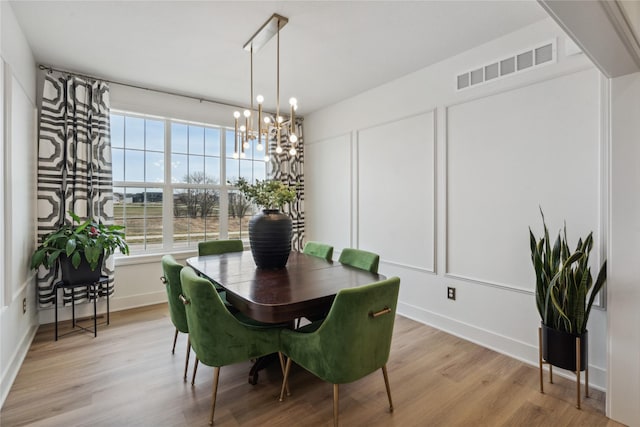 dining room with light hardwood / wood-style floors and a chandelier