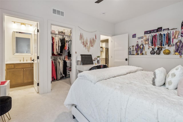 carpeted bedroom featuring ensuite bathroom, a walk in closet, sink, and a closet