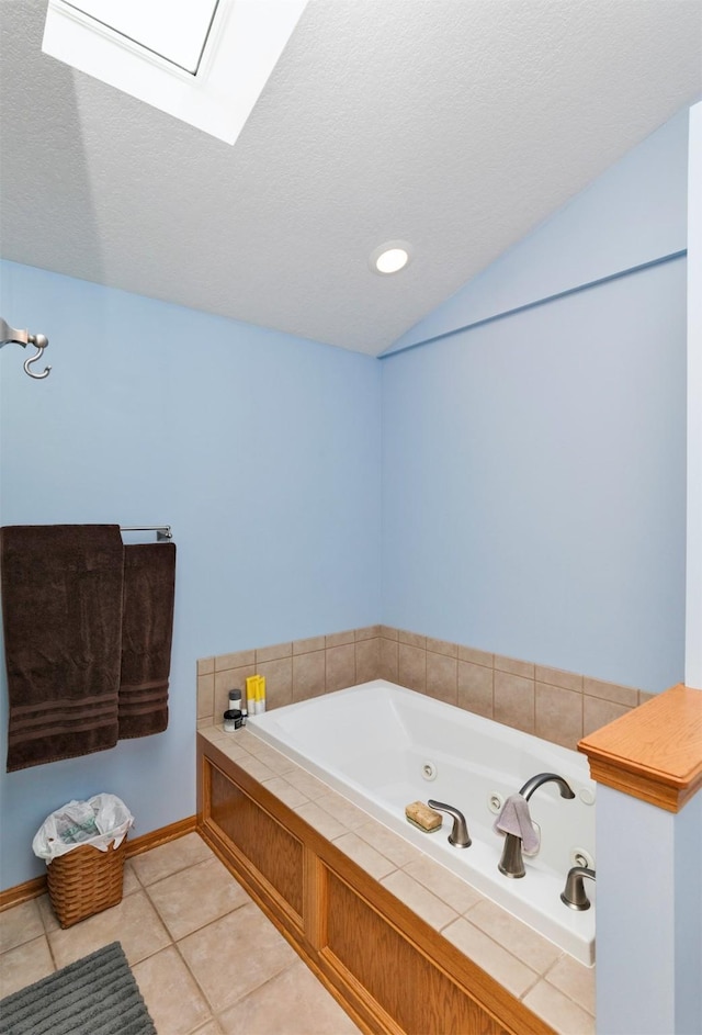 bathroom with a washtub, tile patterned flooring, a textured ceiling, and vaulted ceiling with skylight