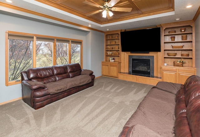 carpeted living room with a tiled fireplace, a tray ceiling, built in features, and ornamental molding