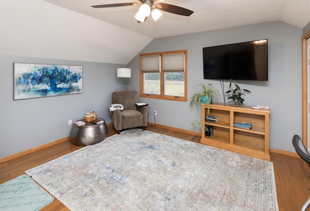 living area featuring ceiling fan, vaulted ceiling, hardwood / wood-style floors, and a textured ceiling