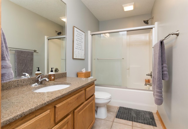 full bathroom featuring shower / bath combination with glass door, tile patterned flooring, vanity, a textured ceiling, and toilet