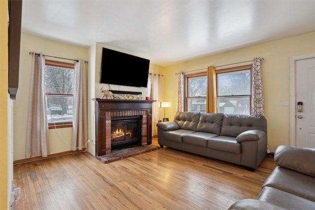 living room with light hardwood / wood-style flooring and a brick fireplace