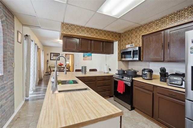 kitchen with a paneled ceiling, dark brown cabinets, sink, and stainless steel appliances