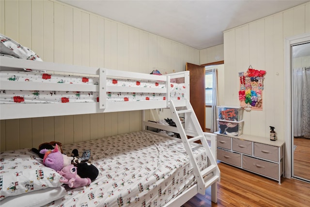 bedroom with light hardwood / wood-style flooring and wooden walls