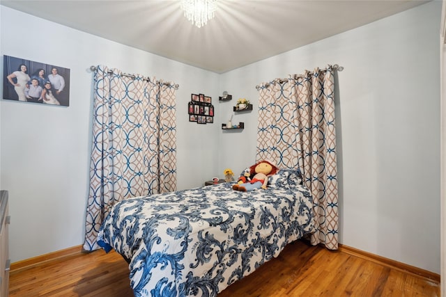 bedroom with hardwood / wood-style floors and a chandelier