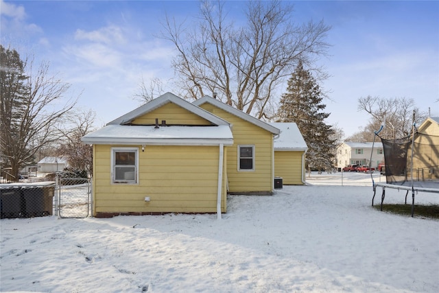 snow covered house featuring central AC unit and a trampoline