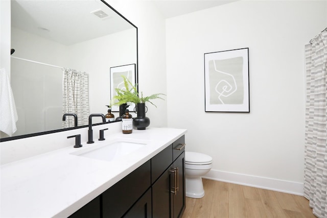 bathroom with walk in shower, vanity, wood-type flooring, and toilet