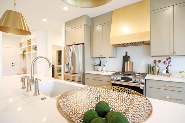 kitchen featuring sink, stainless steel appliances, premium range hood, pendant lighting, and gray cabinets