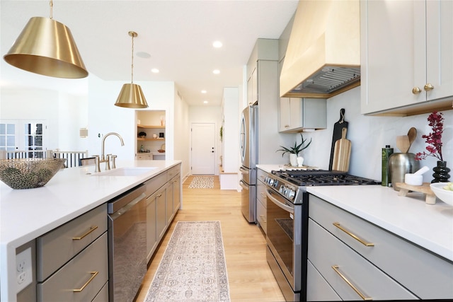 kitchen with gray cabinetry, custom exhaust hood, sink, decorative light fixtures, and stainless steel appliances