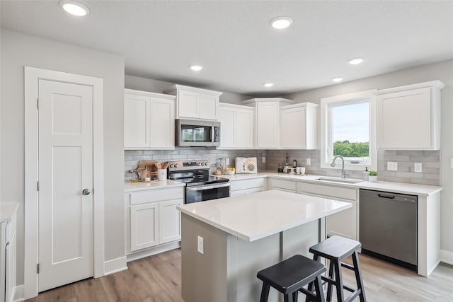 3251 NW Brookside Dr, Grimes, IA 50111 - kitchen with stainless steel appliances, a sink, a breakfast bar, light wood finished floors, and backsplash